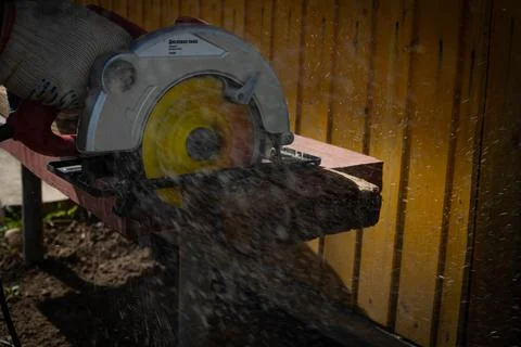 Builder saws a board with a circular saw in the cutting a wooden plank Stock Photos