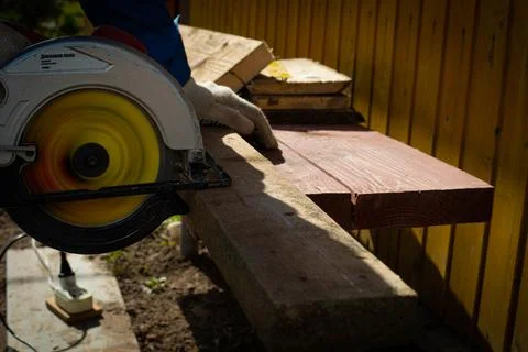 Builder saws a board with a circular saw in the cutting a wooden plank Stock Photos