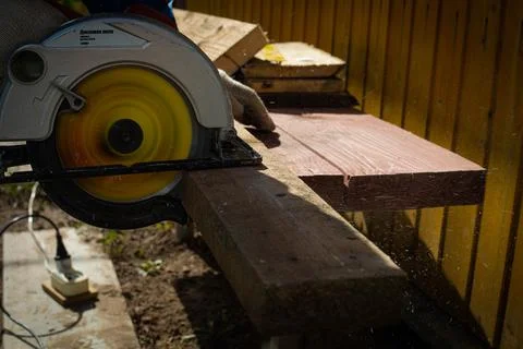 Builder saws a board with a circular saw in the cutting a wooden plank Stock Photos