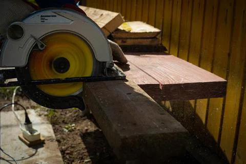 Builder saws a board with a circular saw in the cutting a wooden plank Stock Photos