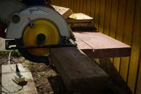 Builder saws a board with a circular saw in the cutting a wooden plank Stock Photos