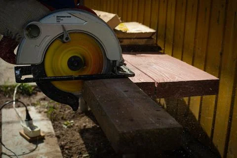 Builder saws a board with a circular saw in the cutting a wooden plank Stock Photos