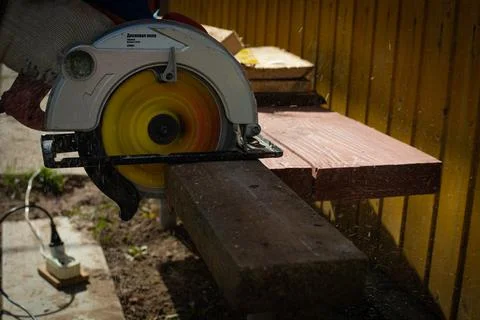 Builder saws a board with a circular saw in the cutting a wooden plank Stock Photos