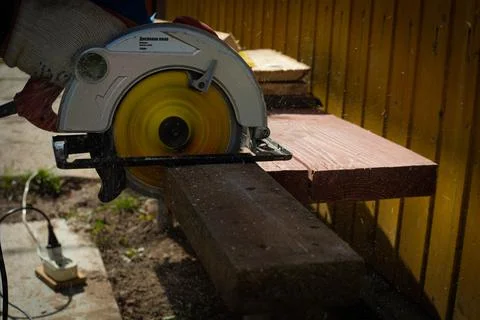Builder saws a board with a circular saw in the cutting a wooden plank Stock Photos