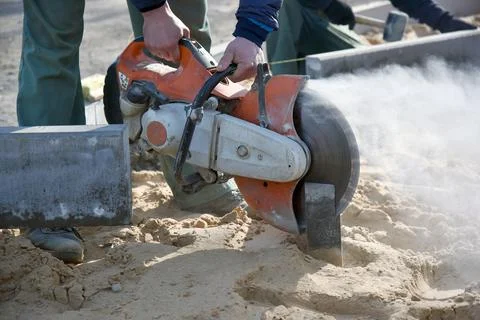 A builder saws a concrete block with a circular saw. Stock Photos