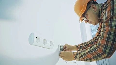 Builder with screwdriver fixing socket indoors Stock Footage 69863915