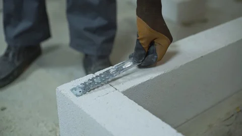 Builder screwing joining clamp in aerated concrete block with electric drill Stock Footage 102906072
