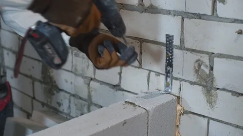 Builder screwing joining clamp in aerated concrete block with electric drill Stock Footage 102908432