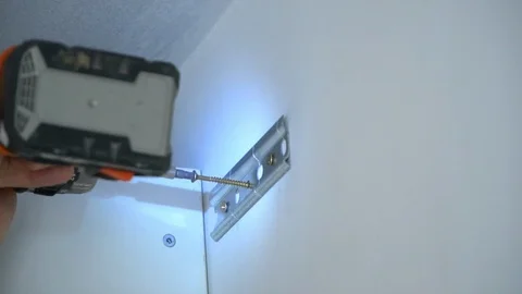 The Builder screws the screw into the wall 库存影片 103949297