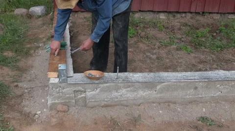 Builder securing wooden planks on cement foundation Stock-Footage 64214664