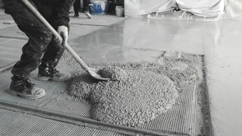 A builder with a shovel distributes the concrete evenly poured into one large Vídeo Stock 290945625