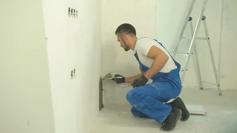 Builder sits and puts mixture on the wall Stock Footage 124850664