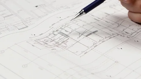 Builder sits at the table, chooses a drawing that is more optimal for him. Close Stock Footage 73674475