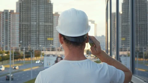 Builder with smartphone at construction site. Builder speaks on cell phone on Stock Footage 91512577