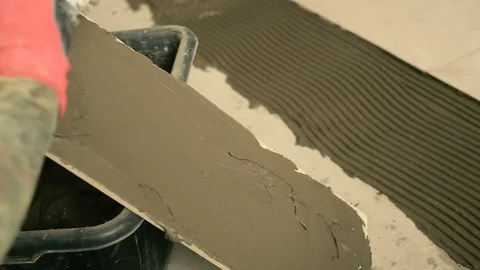 Builder smears the solution on the tile Vídeos de archivo 90782530