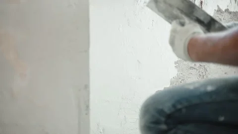 Builder spackling cement wall and angles using metal trowel, spatula and white Stock Footage 148993258