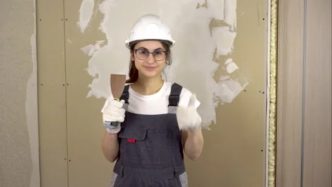 A builder with a spatula in his hand looks at the camera and shows the class and Stock Footage 152037246