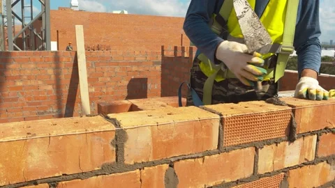 Builder in special clothes lays bricks with a spatula. Work on a summer day Stock Footage 157387136