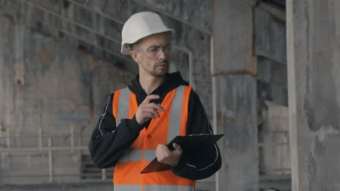 A Builder standing in a building under construction makes notes on a tablet. Stock Footage 131602857