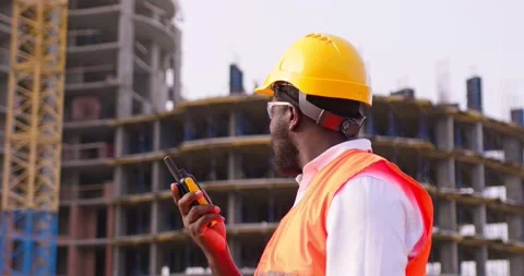 Builder standing in front of the construction site, talking by walkie talkie Stock Footage 172287937