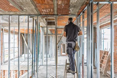Builder standing on ladder on building construction site Stock Photos