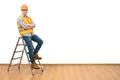 The builder standing on the ladder on the white wall background Photo