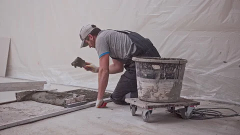 Builder stands on knees and puts mixed concrete on floor Stock Footage 146679979