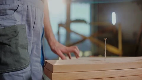 Builder stands in studio, talking and gesturing near a board with a screw in it Stock Footage 170501084