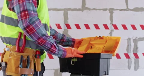 Builder takes measuring tape from toolbox against brick wall Vídeos de archivo 309923413