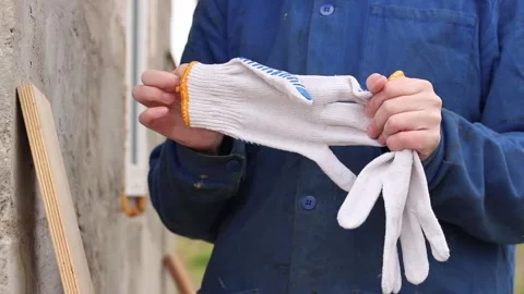 A builder takes off white work gloves after finishing work Stock Footage 334625060