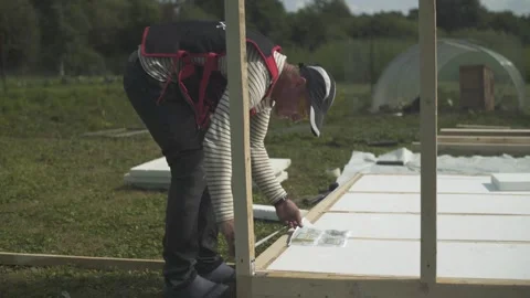 Builder taking measurements and checking design of new hen house at poultry farm Stock Footage 247523539