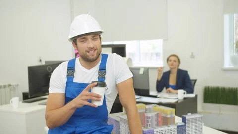 Builder talks something on camera with smile and drinks coffee Stock Footage 121795711