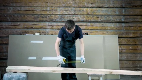 The builder with a tape measure in his hands thought about the size of the board Stock Footage 101384374