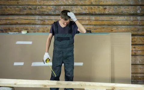 The builder with a tape measure in his hands thought about the size of the bo Stock Photos