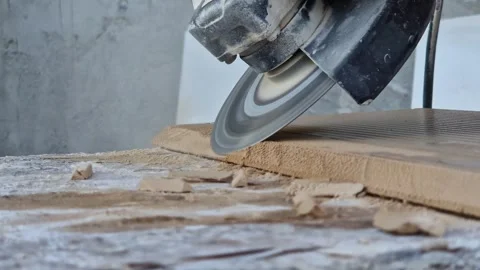 A builder trims the edge of a ceramic tile using an angle grinder 스톡 동영상 344170038