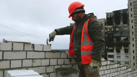 A builder with a trowel in his hands is a treasure of cement and builds a brick Video stock 224720020