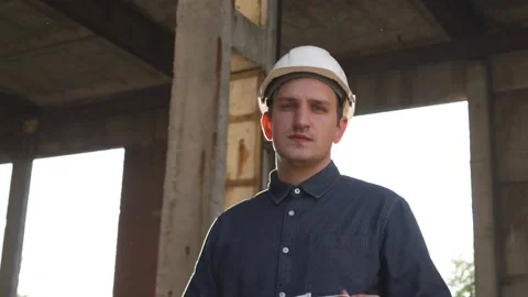 Builder turns to camera, puts on white mask, construction site in the background Stock Footage 138211860