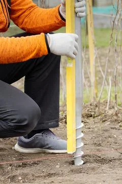 The builder twists the foundation made of screw piles. Lightweight and fast Stock Photos