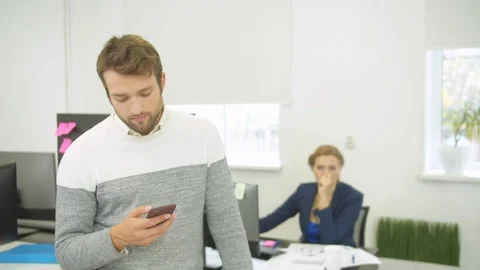 Builder types something on phone, woman behind him looks on schemes of houses Stock Footage 121795172