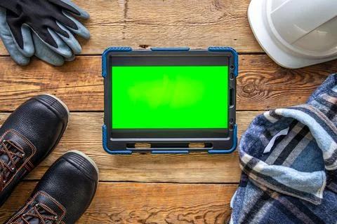Builder uniform and digital tablet on wooden background, flat lay. Stock-Fotos
