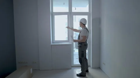 A builder in uniform checks the size and quality of window installation in a new Stock Footage 170045522