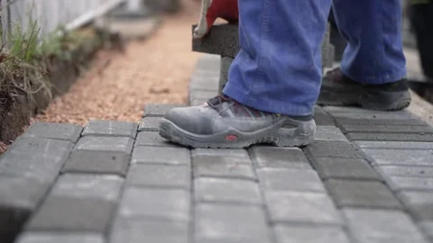 Builder in uniform laying paving tiles on the construction site with white ho Video stock 270556610