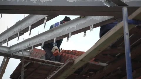 Builder in uniform puts bricks standing on roof carcass Stock Footage 314648485