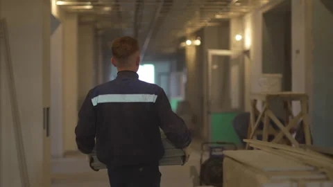 Builder in uniform walks through unfinished hallway Видео 311893792