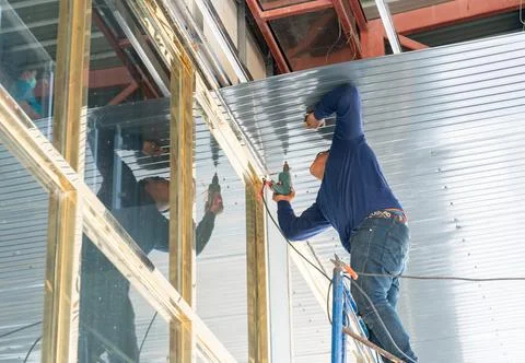 Builder use electric screw driver install metal sheet ceileng. Stock Photos