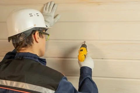 The builder uses a drill for repairs. Concept of professional home renovation Stock Photos