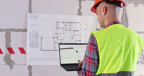 Builder uses modern technology to study flat layout on laptop Stock Footage 309927512