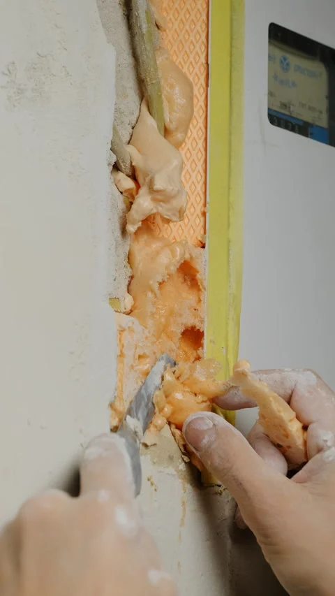 Builder uses utility knife to trim excess construction foam Stock Footage 317084370