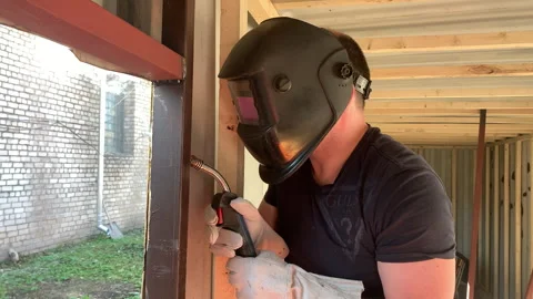 A builder uses a welding machine to make a window frame. Stock Footage 310652791