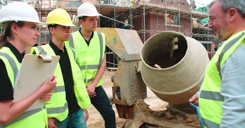 Builder Using Cement Mixer On Building Site With Apprentices Stock Footage 56221504